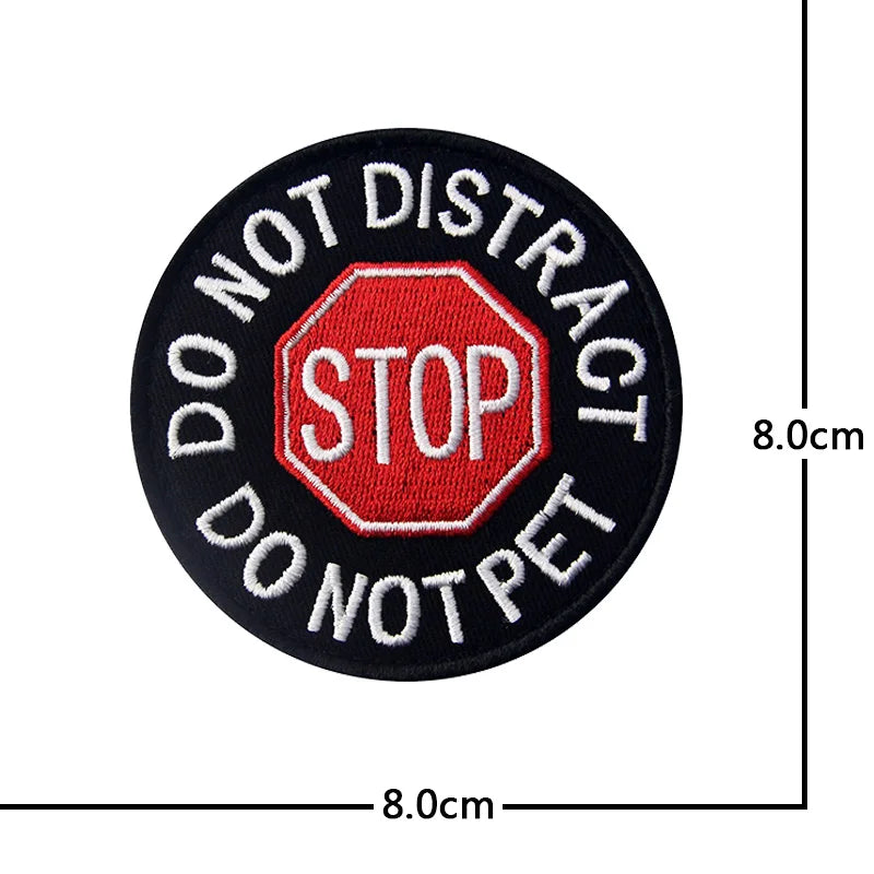 Black embroidered patch with red text STOP DO NOT DISTRACT DO NOT PET on a hexagonal background
