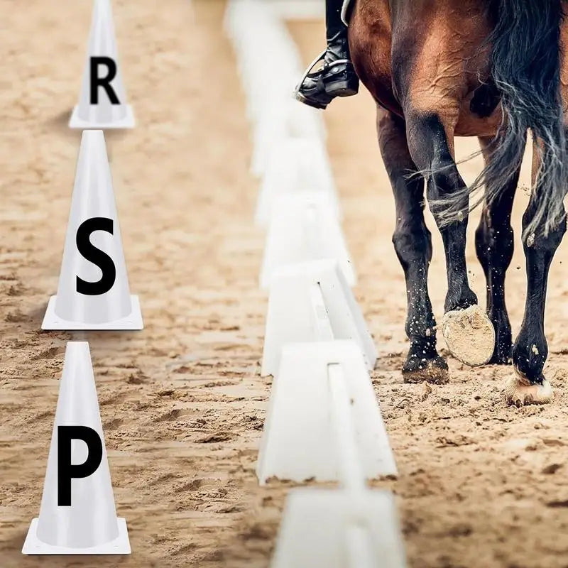 Cônes d'entraînement de dressage avec les lettres R, S et P alignées sur un parcours de terre à côté d'un cheval.