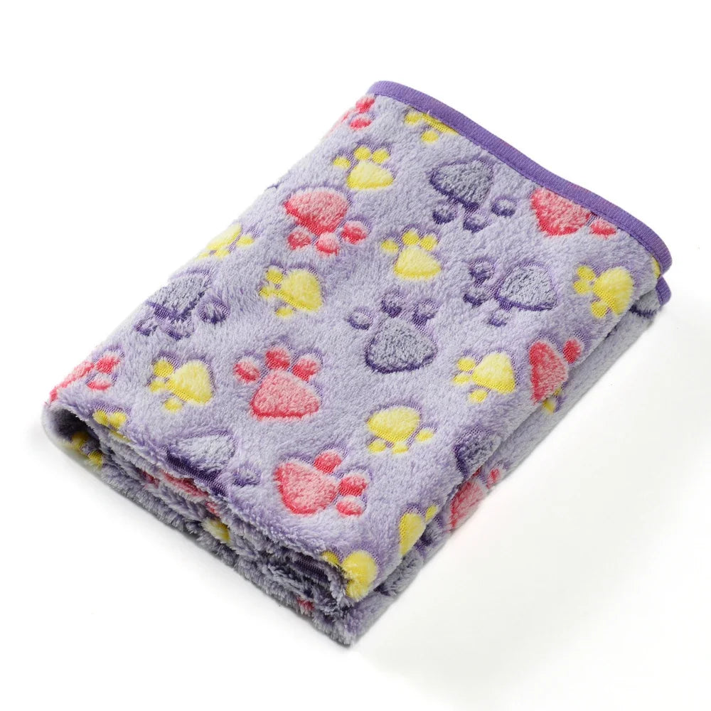 A purple fleece pet blanket featuring a pattern of pink, yellow, and purple paw prints.