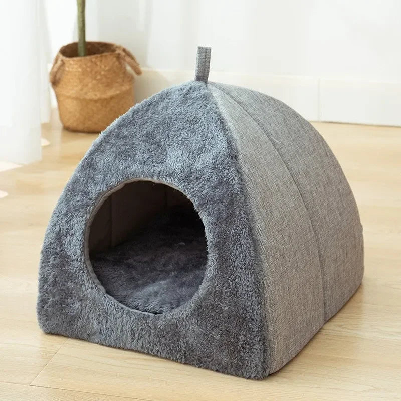 Un lit pour chat en velours gris en forme de dôme avec une entrée, posé sur un plancher en bois.