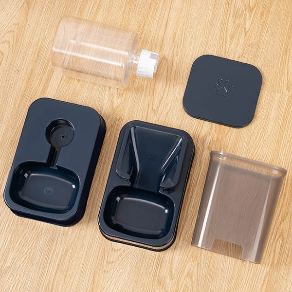 A set of automatic pet feeder components including a clear dispenser, a dark feeder unit, and a transparent food tray on a wo