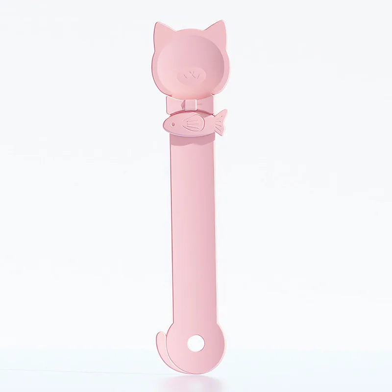 Cuchara dispensadora de comida para gatos rosa con forma de cabeza y pescado en el mango.
