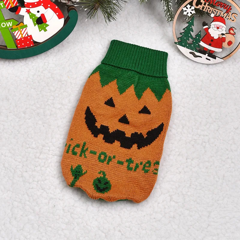 A knitted orange pumpkin shaped sweater with a black carved face and green details, resting on a white surface.