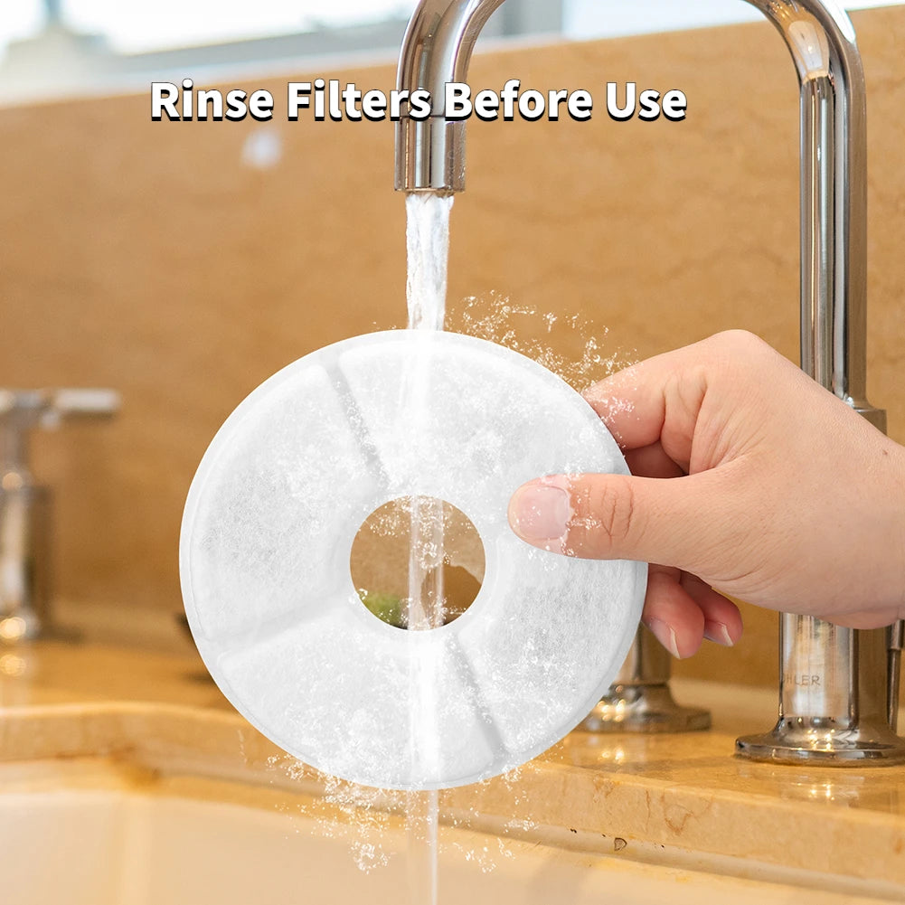 A hand is rinsing a white replacement filter disc under a faucet before use.