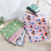 A pink and green patterned washable pet training mat for dogs is displayed on a white table.