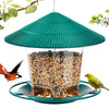 Nourrice à oiseaux suspendue, verte et étanche, avec un toit conique rempli de graines, tenue par un fil.