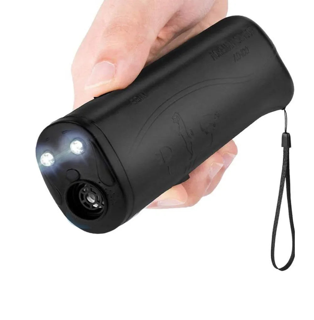 Eine Hand hält ein schwarzes Ultraschall-Hundbell-Abwehrmittel mit LED-Taschenlicht.