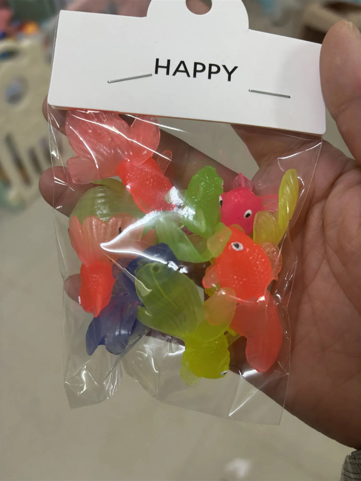 A clear plastic bag filled with ten colorful soft rubber goldfish bath toys, including red, orange, green, and blue varieties