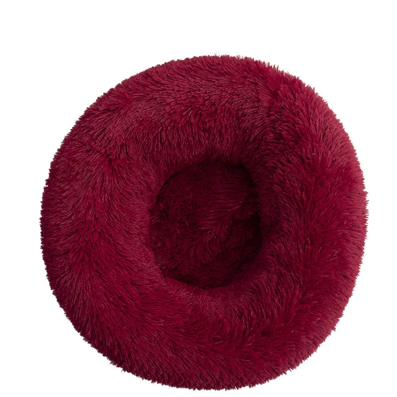 A round, deep burgundy plush pet bed for dogs and cats.