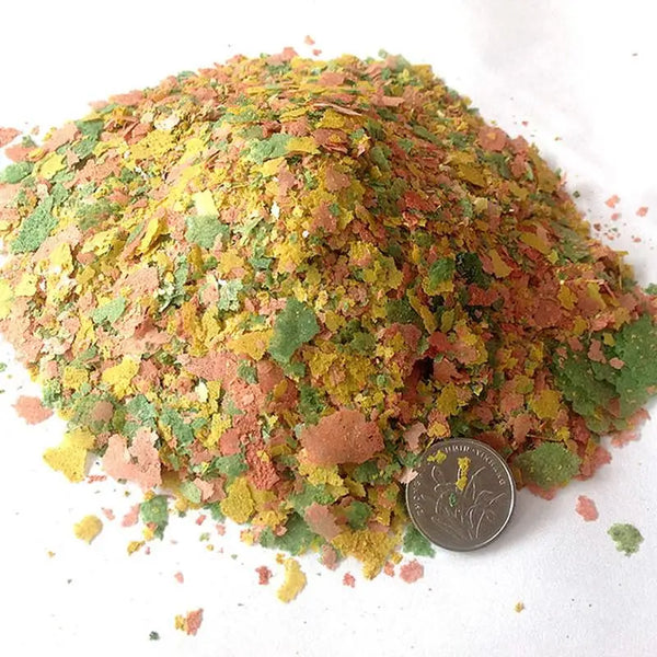 A pile of green and orange flakes used as food for tropical fish.