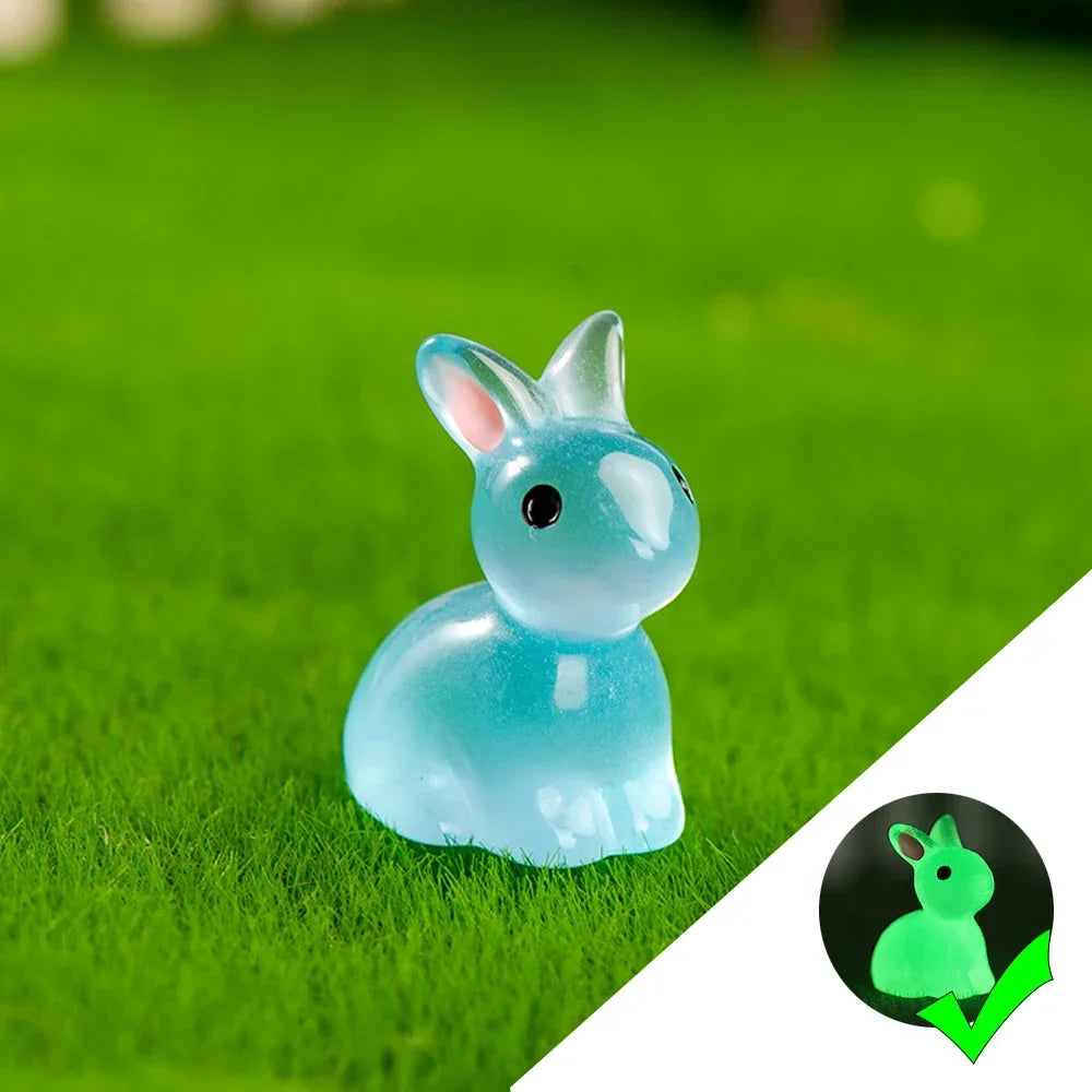 A small, translucent blue glow-in-the-dark resin bunny figurine sitting on bright green grass.