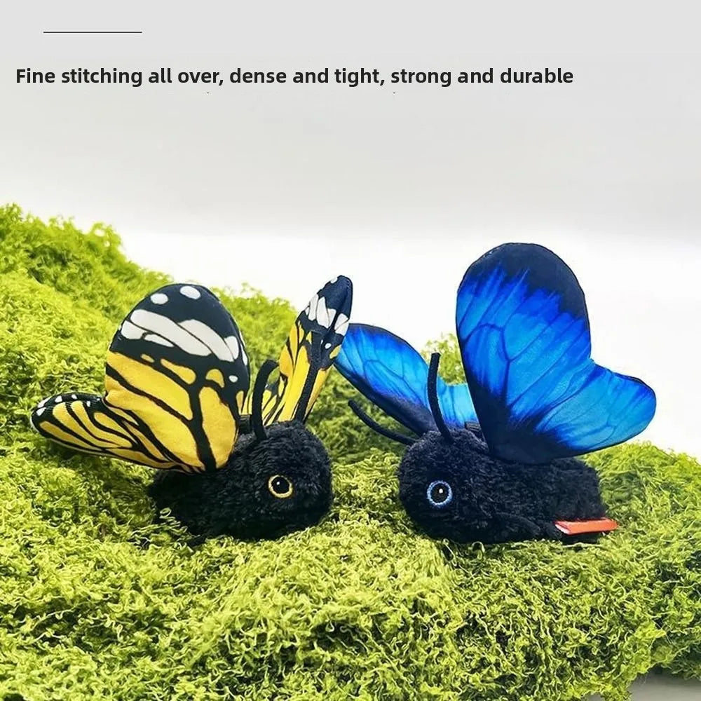 A black cat toy with blue and yellow butterfly wings is resting on green moss.