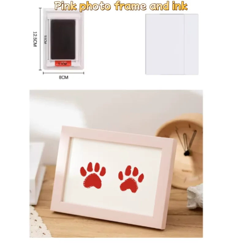 Rosa Fotorahmen mit einem Tintenpad und einem roten Pfotenspuren-Design auf einer Holzoberfläche.