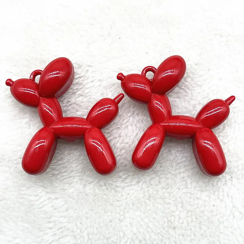 A pair of bright red acrylic balloon dog charm pendants for jewelry making and keychains.