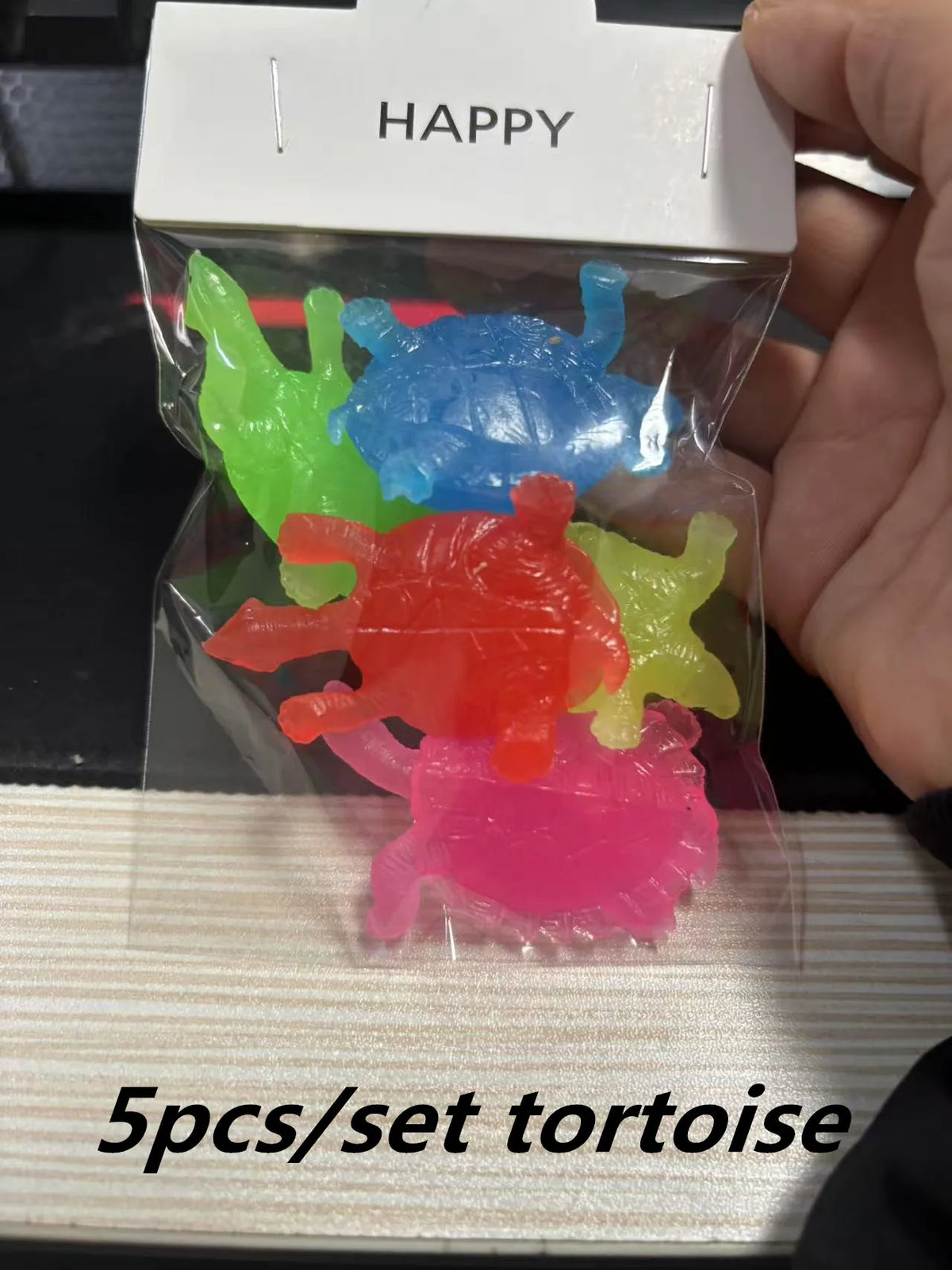 A clear plastic package containing five brightly colored soft rubber toys shaped like tortoises for bath time.