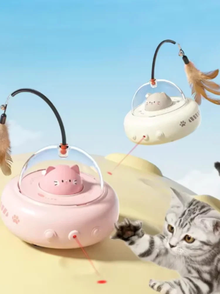 A pink interactive rotating feather cat toy is shown hovering above a yellow surface, with a gray tabby cat interacting with 