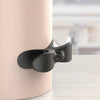 A black silicone cable organizer is attached to a light pink cylindrical object.