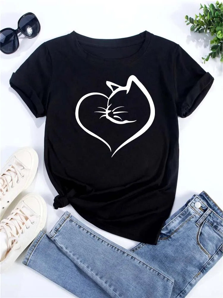 Camiseta negra de manga corta con silueta blanca de la cabeza de un gato en el pecho, junto a jeans y gafas de sol.