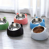 A collection of colorful, tilted stainless steel pet bowls sitting on a light wooden floor.