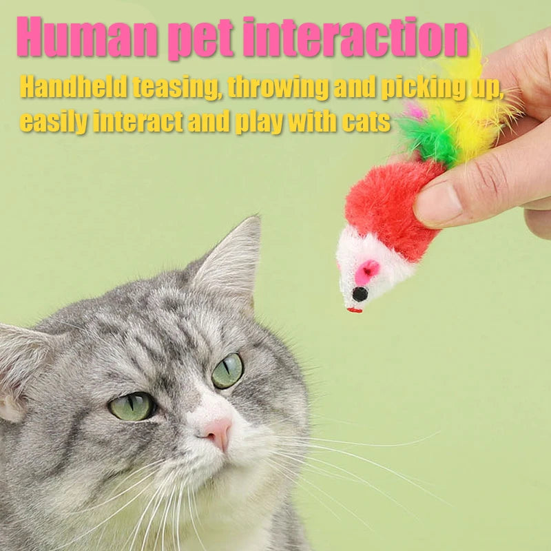 A hand is interacting with a plush mouse cat toy featuring a red body and yellow feather tail near a domestic cat.