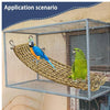 A blue and yellow parrot is perched on a woven hammock inside a wire cage.