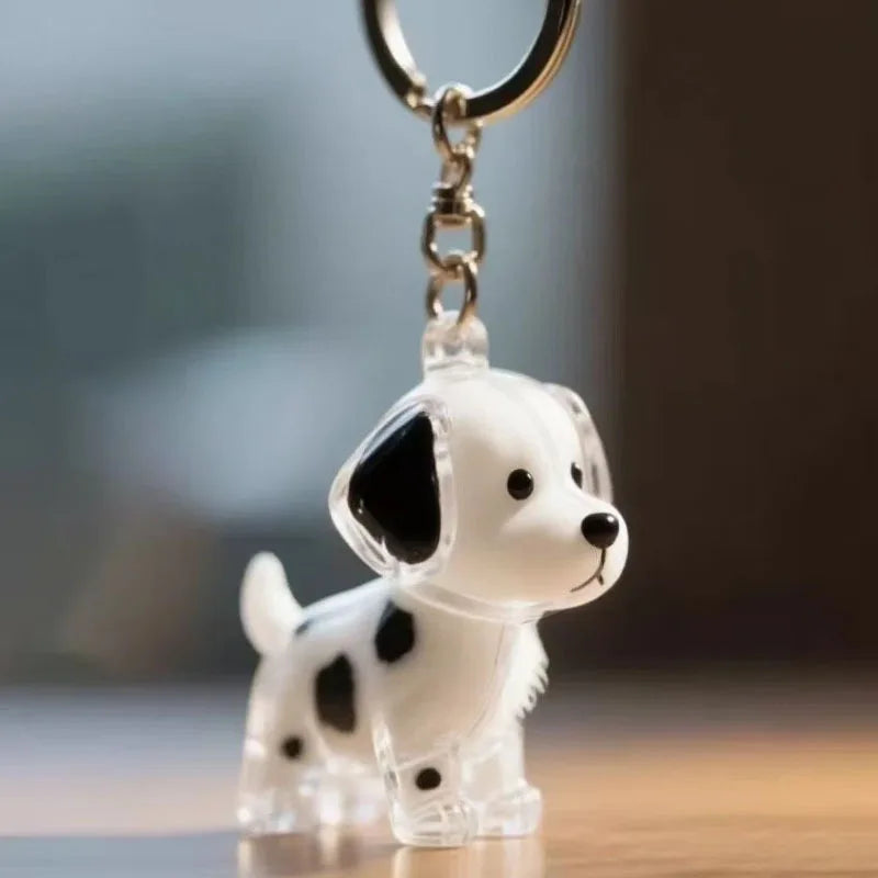 Figurine en plastique transparent d'un chien blanc et noir fixé à un anneau de clé argenté.