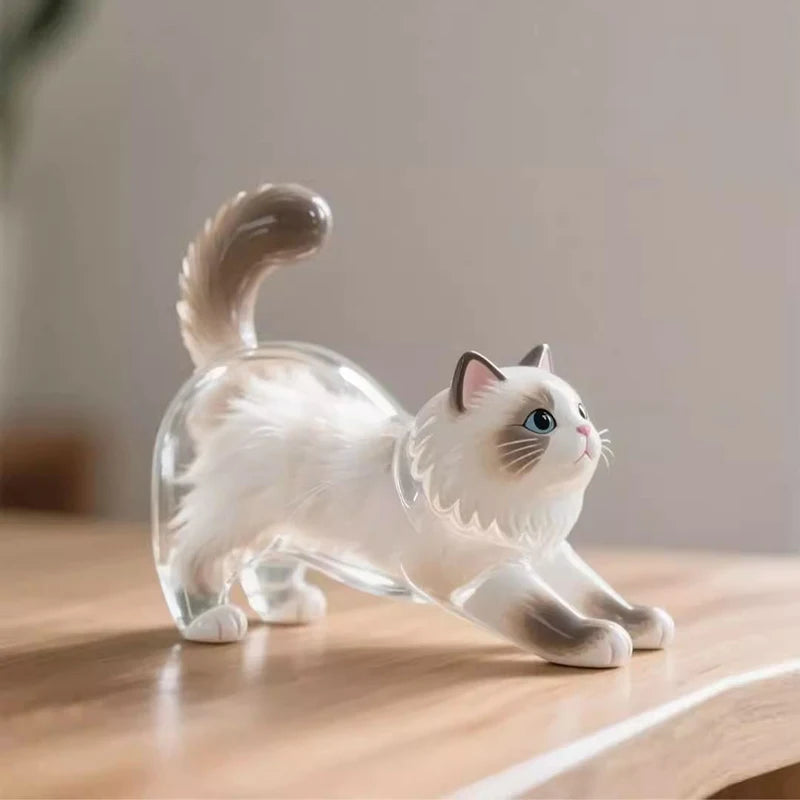 Klare Glasfigur einer weißen Katze mit geschwungenem Schwanz auf einer Holzoberfläche.