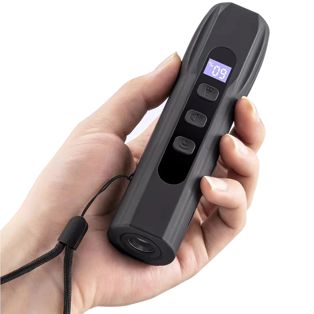 Eine Hand hält ein schwarzes tragbares Ultraschallgerät zum Training und Abschrecken von Hunden mit digitaler Anzeige.
