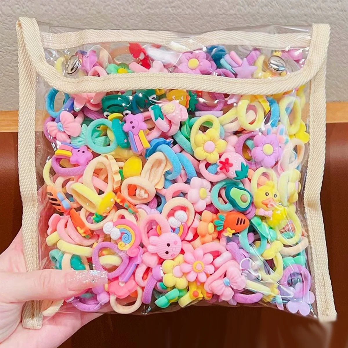 A clear plastic bag filled with colorful elastic hair ties featuring cute cartoon characters and shapes.