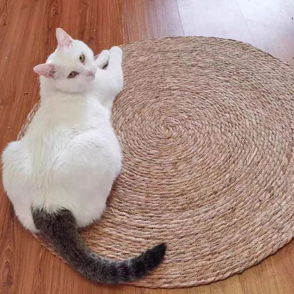 A white and gray cat is lying on a round natural rattan mat.