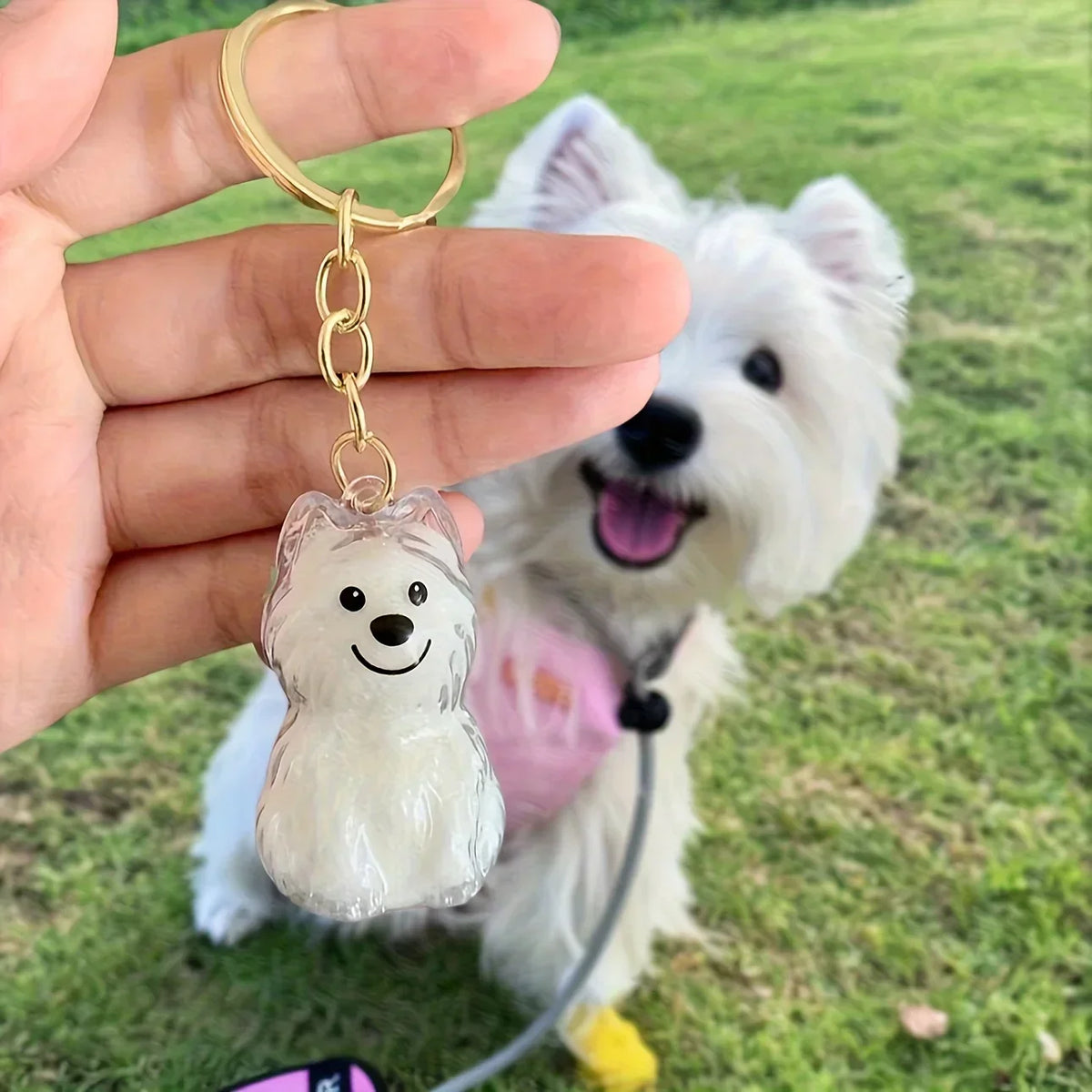 A clear, sculpted dog figurine keychain with a gold-colored ring attached to a leash.