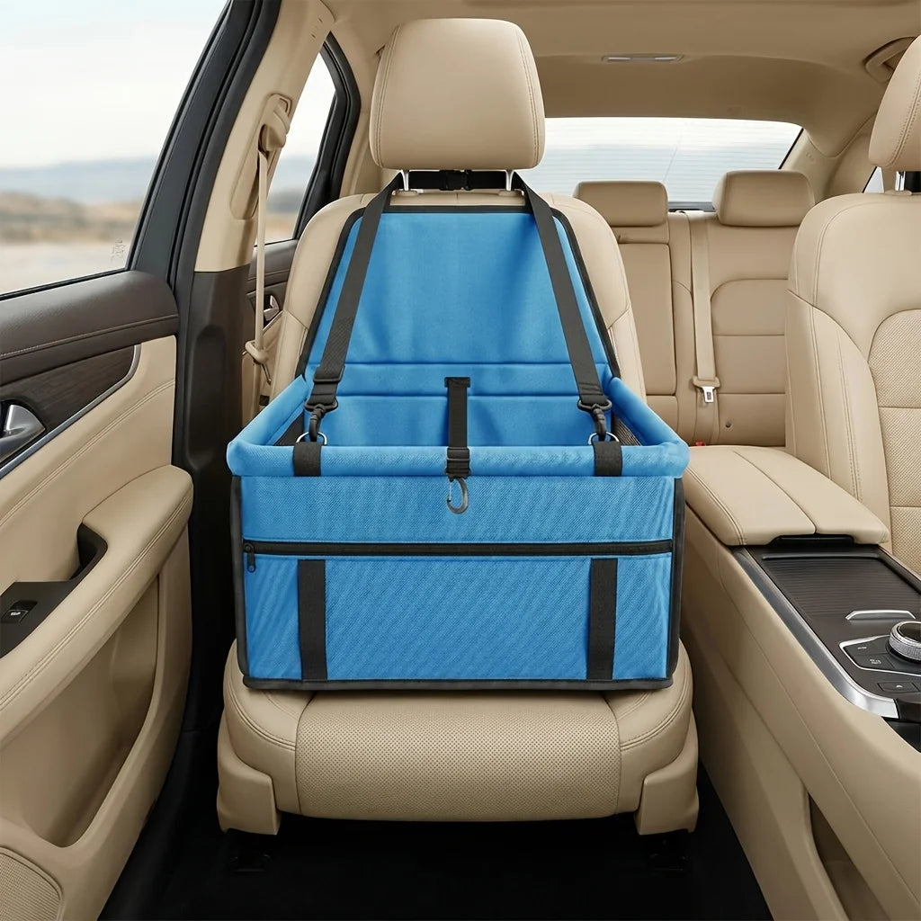 A blue portable dog car seat travel carrier with safety straps is shown installed in the back seat of a car.