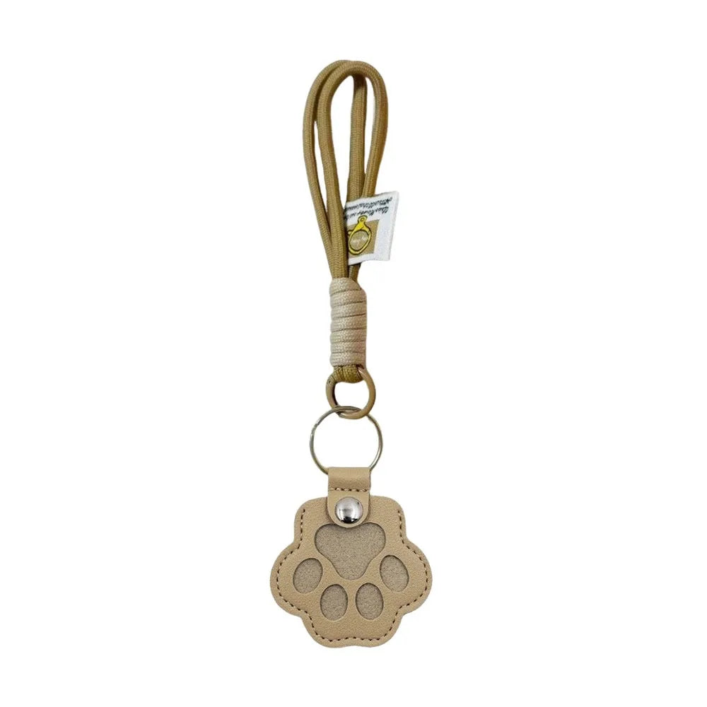 A beige refillable pet hair keychain featuring a cat paw charm attached to a braided cord.