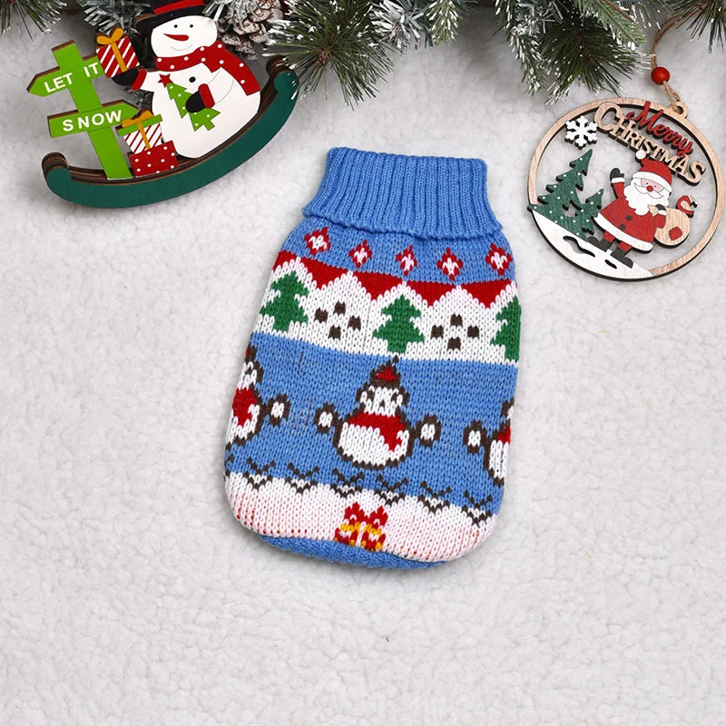 A knitted blue and white winter dog sweater featuring festive Christmas patterns and a small snowman design.