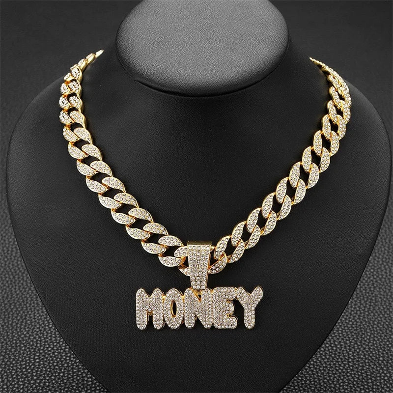 Gold iced out letter M pendant Cuban link chain necklace displayed on a black display stand