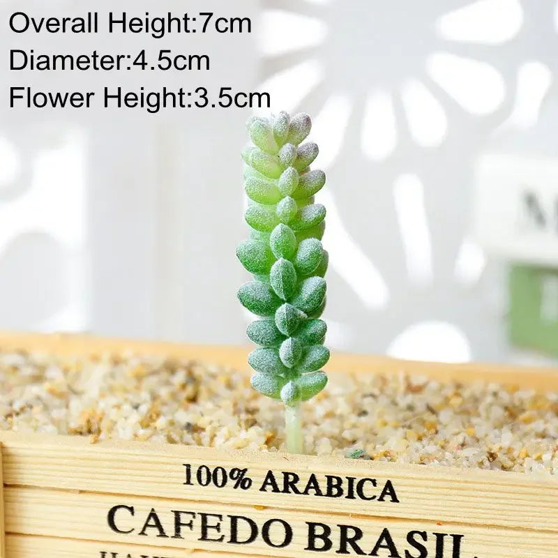 A small, flocked artificial succulent plant with a green stem is displayed in a wooden box filled with light-colored gravel.