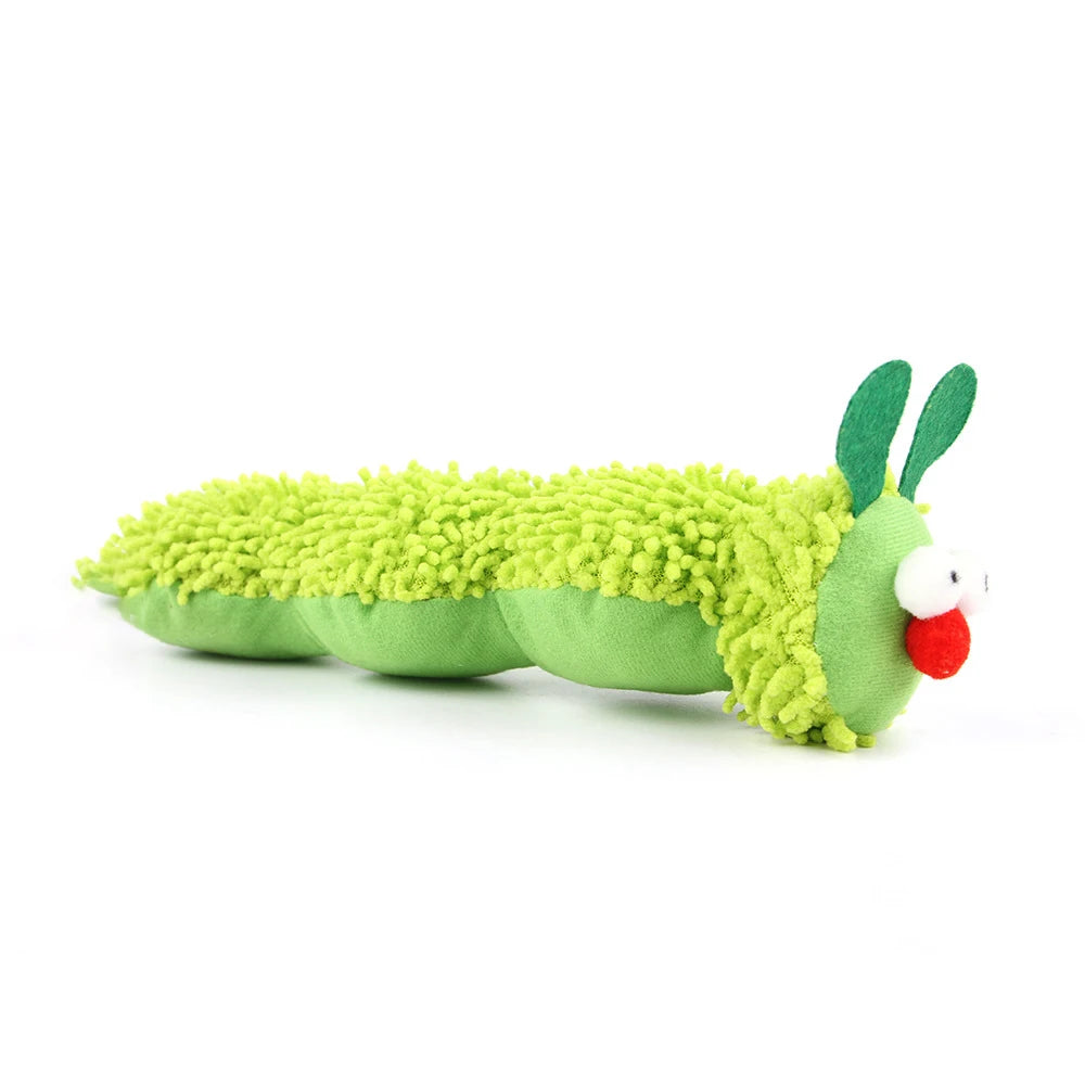 Jouet en forme de chenille verte avec yeux blancs et bouche rouge, fait de tissu doux.