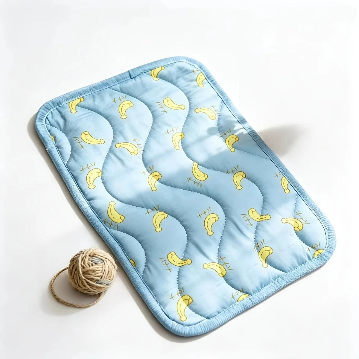 Light blue quilted pet mat featuring a repeating pattern of yellow curved shapes for dogs and cats
