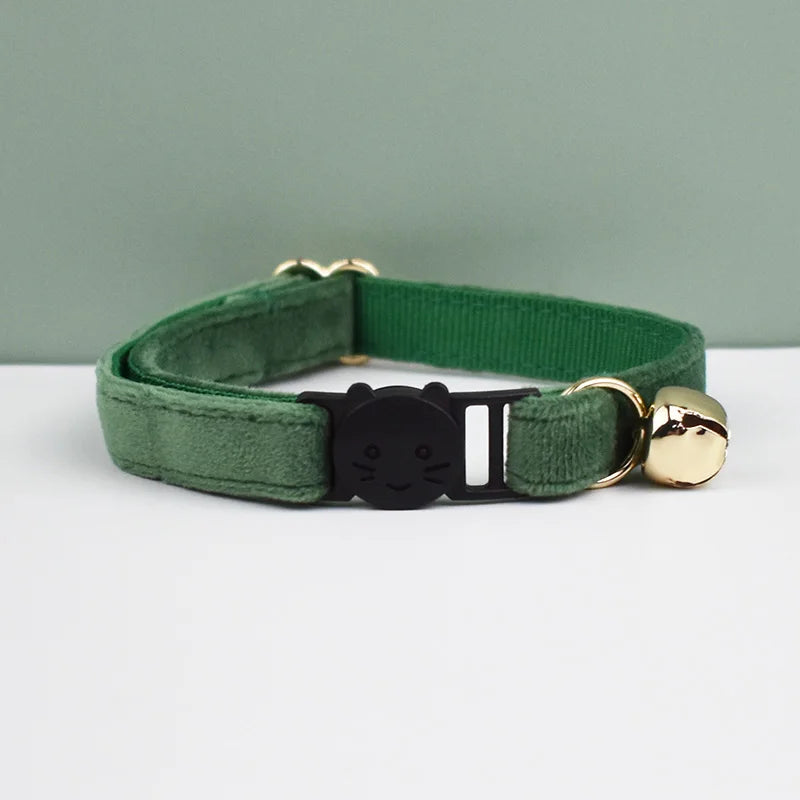 A green velvet cat collar with a black cat charm and gold-toned hardware.