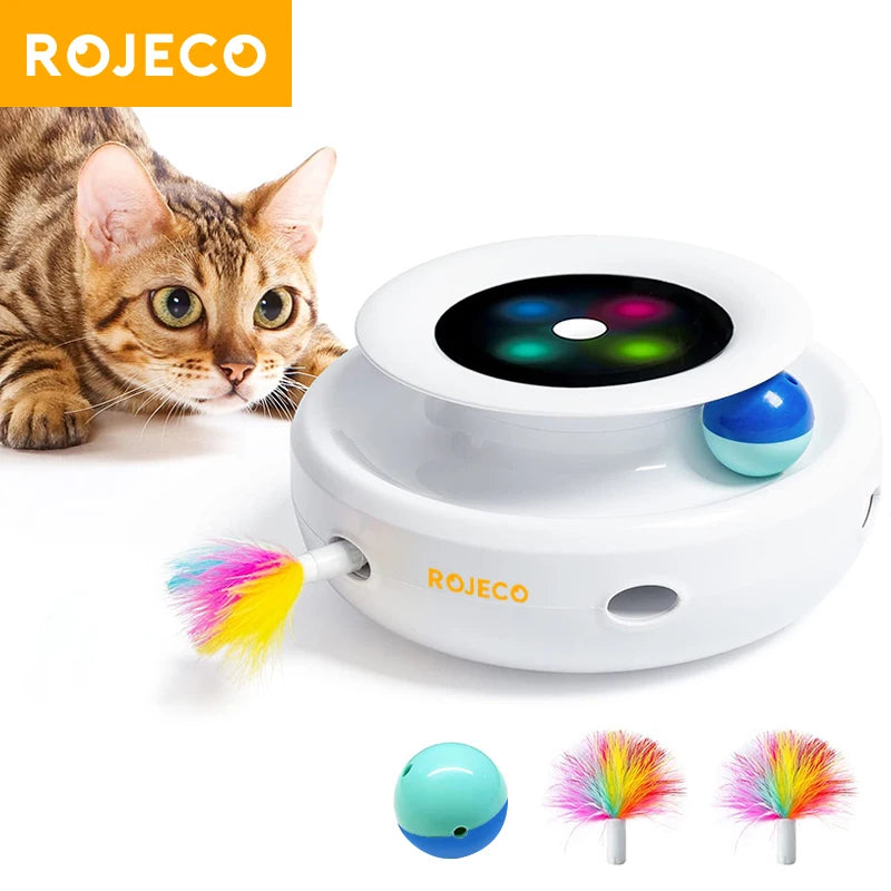 Weißes interaktives Spielzeug für Katzen mit rotierndem Feder und blauer Kugel, mit einer gestreiften Katze in der Nähe.