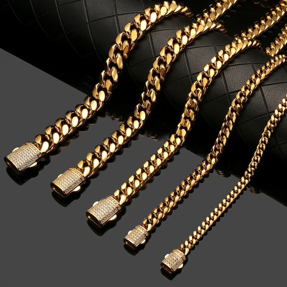 Gold stainless steel curb chain bracelets laid out on a dark surface.