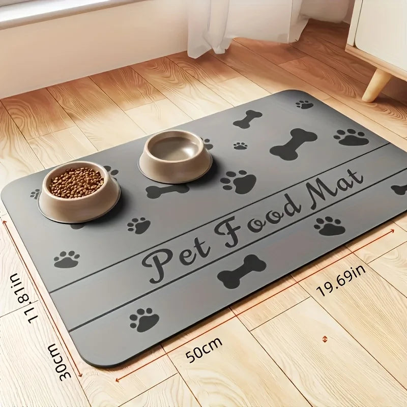 A gray pet food mat with paw and bone designs is placed on a wooden floor, showing its size relative to the room.
