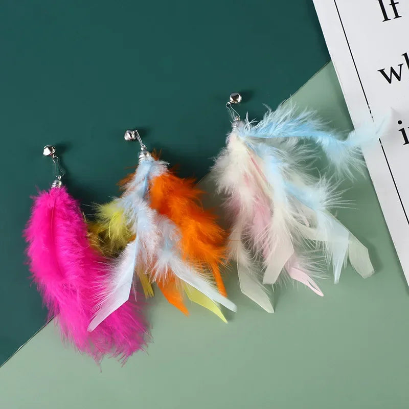 Eine Sammlung farbenfroher Katzenfederspielzeuge mit rosa, orange, gelben und blauen Federn auf grünem Hintergrund.