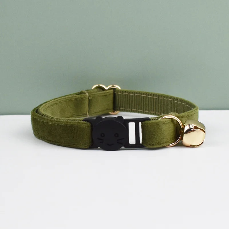 A olive green velvet cat collar with a black cat charm and gold-toned hardware.