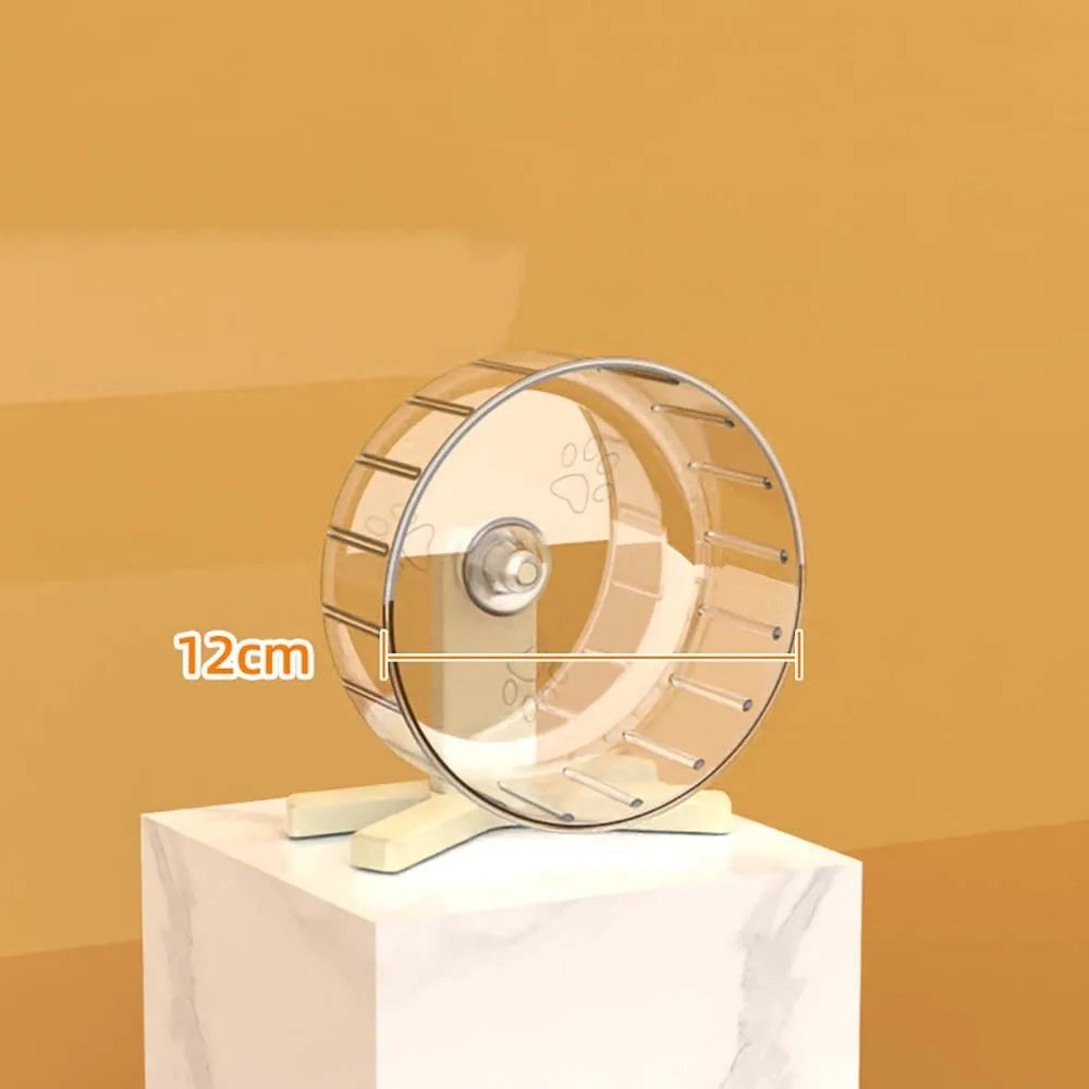A transparent hamster exercise wheel with a silver frame is displayed on a white marble surface.