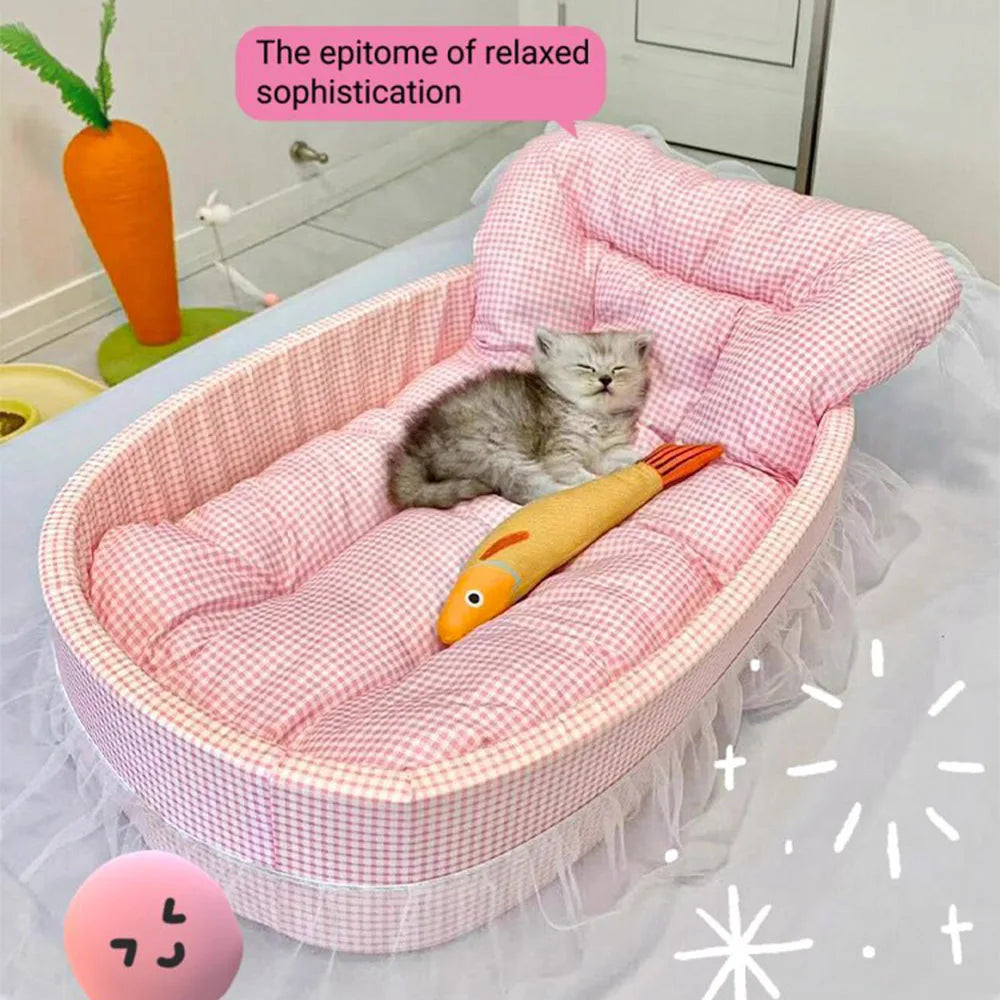 A pink lace-trimmed plush pet sofa bed with a gray kitten resting inside.