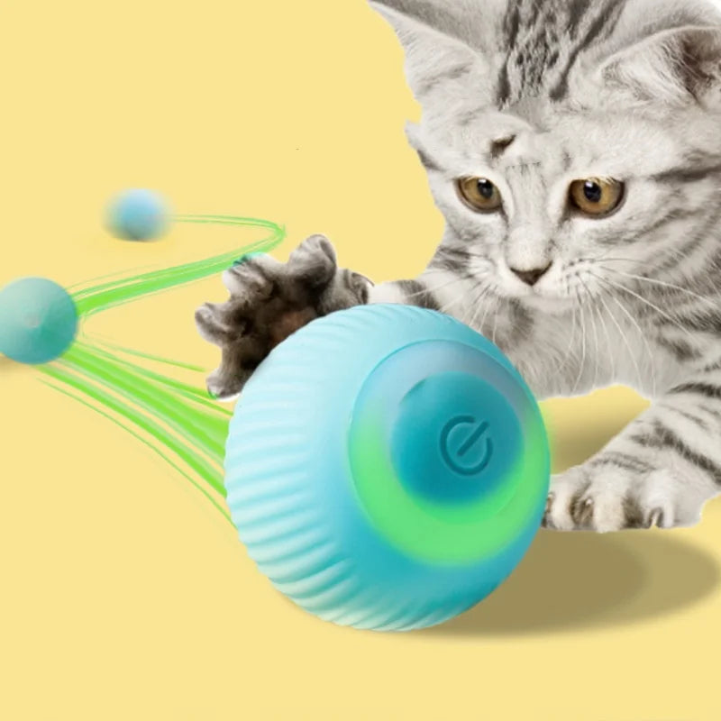 A tabby cat is interacting with a glowing blue electronic ball and green light trails.