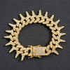 A gold spiked Cuban chain bracelet adorned with diamond accents.