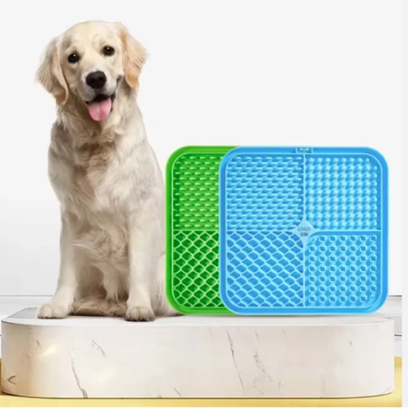 Ein helles Hund sitzt neben einer grünen und blauen Silikon-Lickmatte für Hunde.