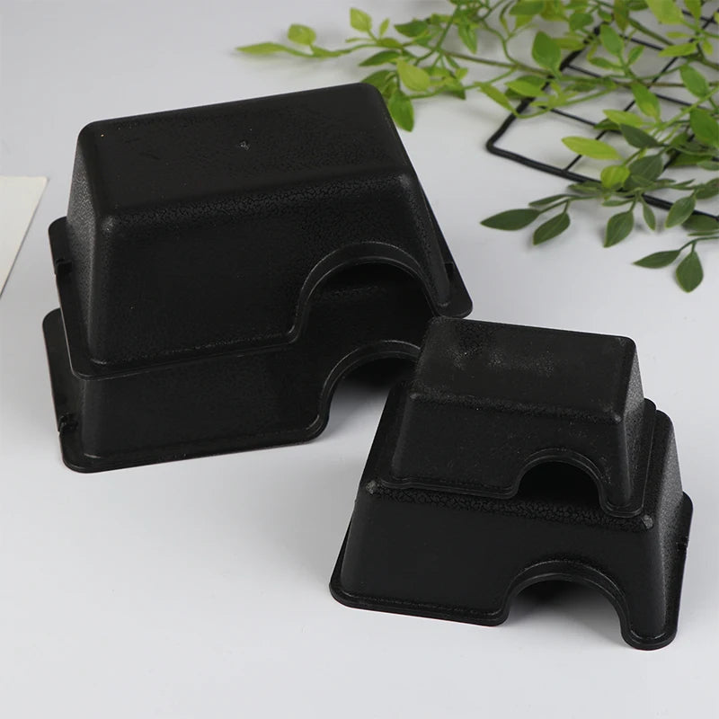 Black reptile hide box enclosure with a textured, rectangular design placed on a white surface.